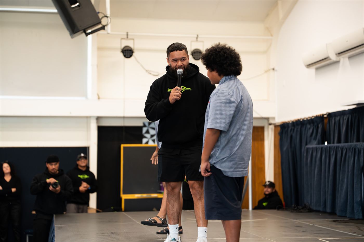 Montel Tivoli talking with a student on stage at a school session.